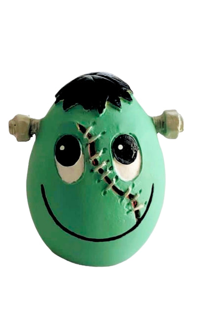Frankie__Frankestein_huevo_de_latex_de_Lanco_para_perros. De color verde, con un poco de pelo negro, tornillos a los lados con alta resistencia al roerlos, cicatriz desde la frente hasta la boca, y mirada y boca sonrientes.