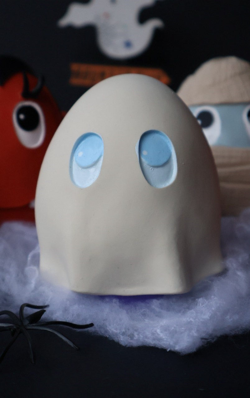 Huevo con forma de Fantasma en color blanco con iris en azul y pupila pequeñita en blanco, tiene forma de sábana y la base se ve poco en color morado para similar el reflejo del suelo en forma de aura.